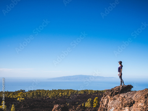 Woman standing on top of a mountain looking far away © doleesi