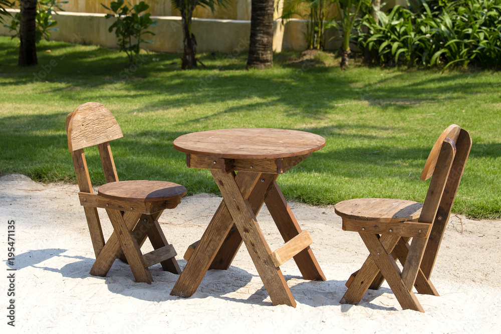 Table and wooden chairs in tropical garden next to the sea on the sand beach, Thailand. Close up Table and wooden chairs in tropical garden next to the sea on the sand beach, Thailand. Close up