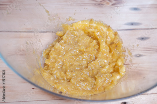 Young Asian boy mash the bananas in large bowl. photo