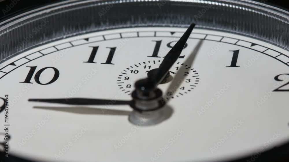 Closeup on slowly rotating clock face with fast moving clock hands