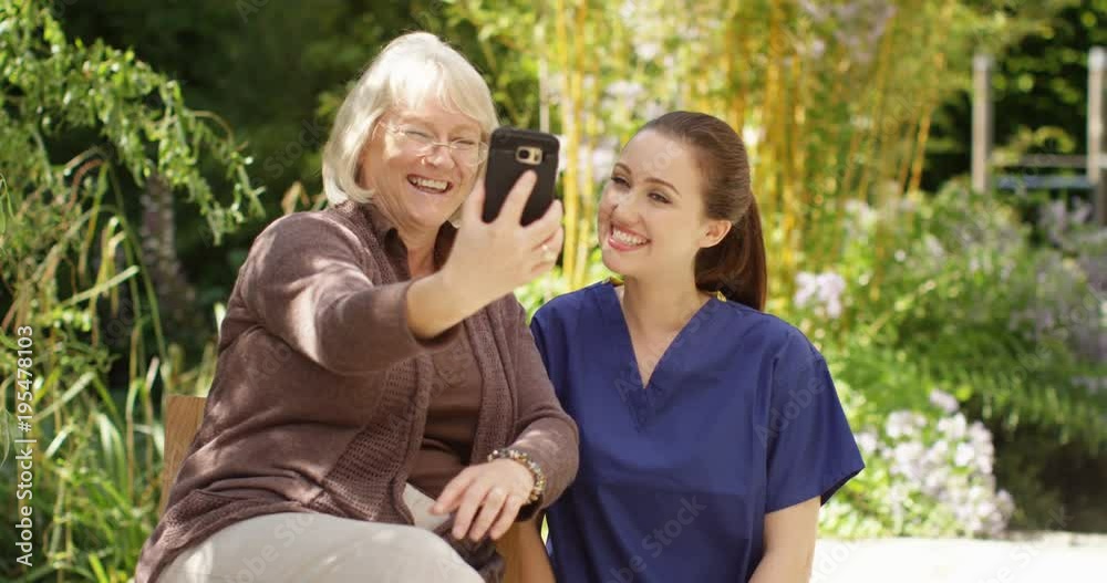 4K Happy senior lady & young nurse, posing for selfie in the garden on a sunny day. Slow motion 4K Happy senior lady & young nurse, posing for selfie in the garden on a sunny day. Slow motion