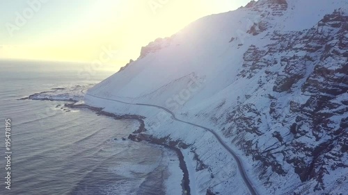Aerial footage of beautiful winter Icelandic landscape. Snow covered mountains by ocean in bright sunny day. Dramatic frozen countryside in Iceland.