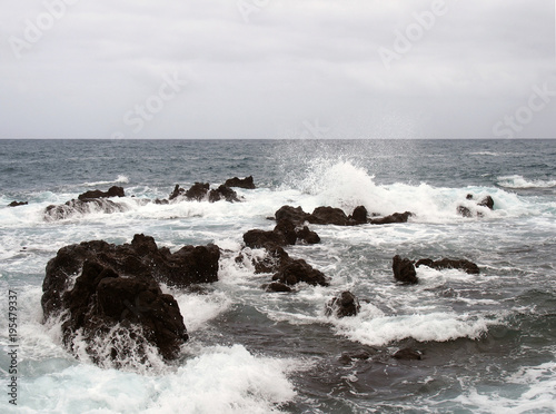 seascape with stormy dramatic waves breaking over coastal rocks with white surf
