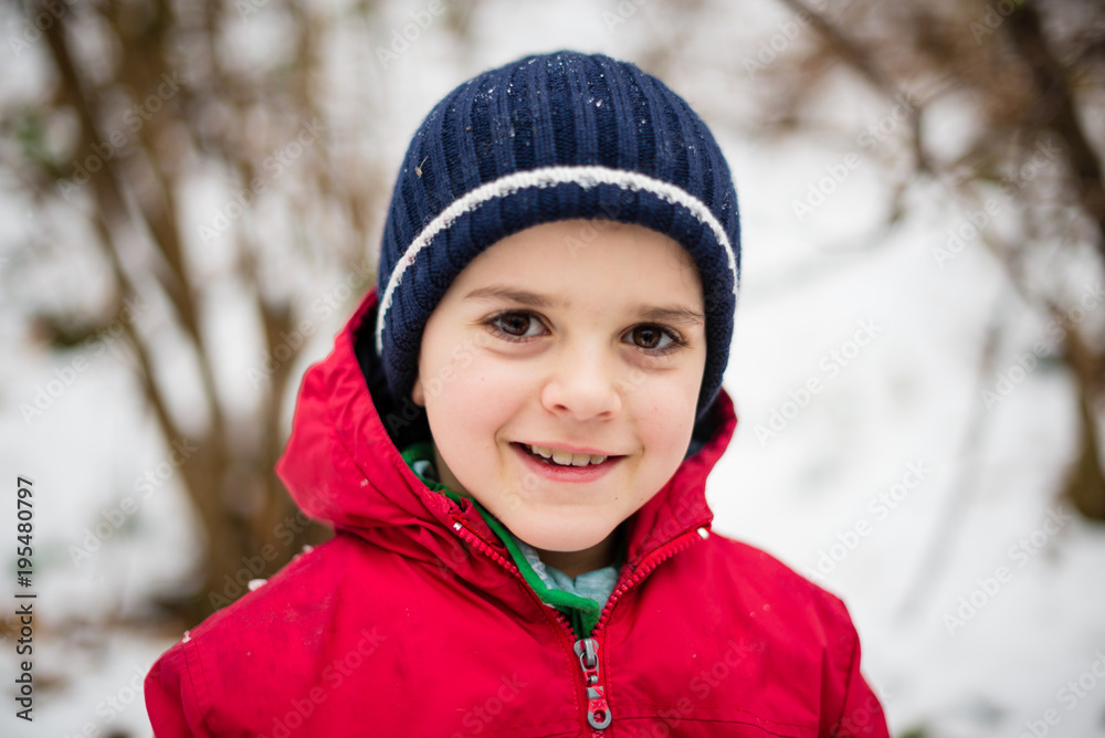portrait of child with woolen hat in snowy forest, smiling