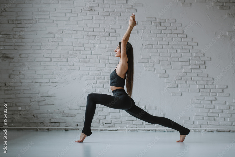 Slim woman practices yoga in white backlit studio Slim woman practices yoga in white backlit studio