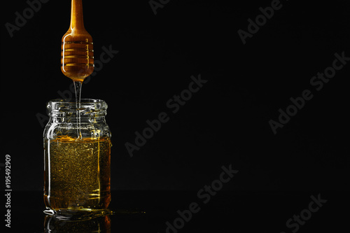 Honey jar with dipper and flowing honey photo