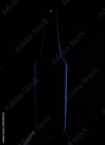 Close-up image. Bottle on a dark background with  blue glare on the sides of the glass.