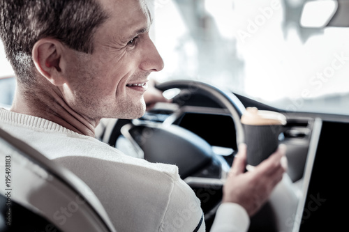 On my way. Happy positive joyful man sitting behind the wheel and holding a cup with coffee while driving his car © Viacheslav Yakobchuk