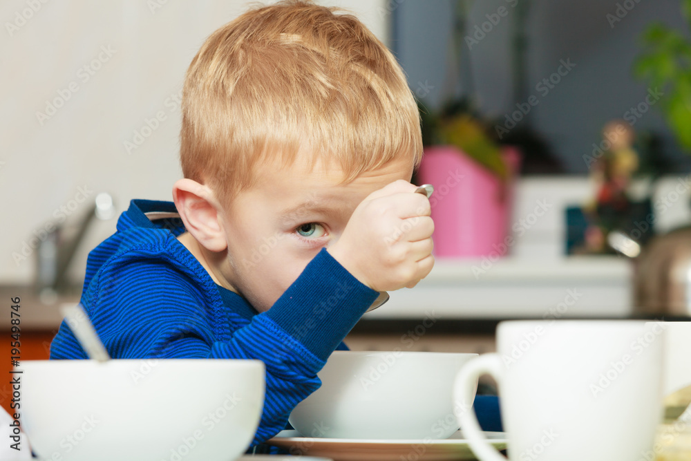 Kid boy eating breakfast, cereals and milk in bowl Kid boy eating breakfast, cereals and milk in bowl
