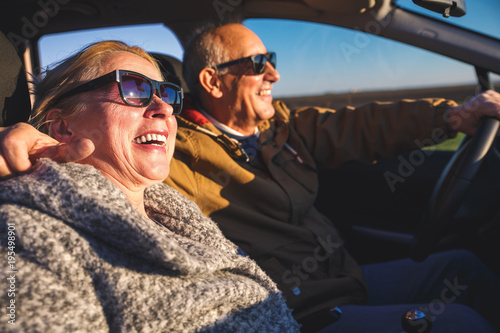 Portrait of smiling elderly couple driving car. 