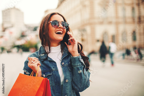 Beautiful young woman talking on the phone in the city after shopping