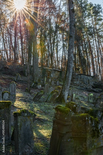 Sonnenstrahlen auf einem alten jüdischen Friedhof mit verwitterten Grabsteinen, Deutschland