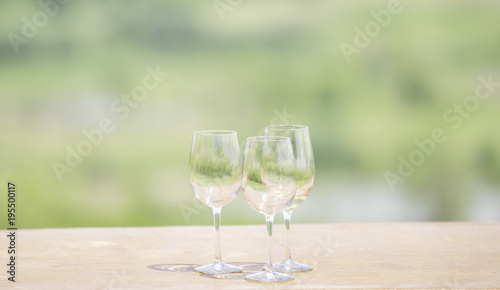 Three glasses of wine on green blurred background.