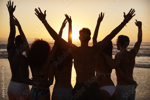 Silhouette Of Friends On Beach Vacation Watching Sunset Over Sea