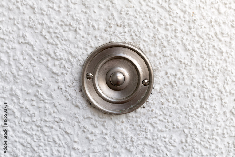 Edelstahl Türklingel an einer weissen Wand Edelstahl Türklingel an einer weissen Wand