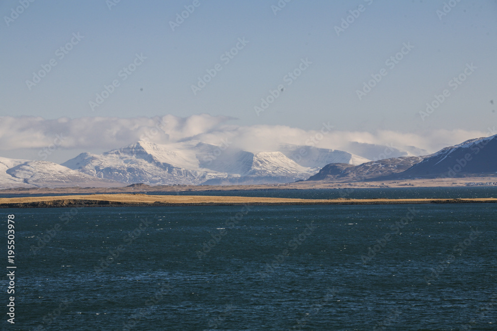 Island landscape with the sea and snow mountains and the blue sky