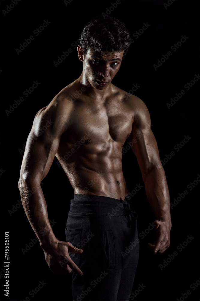 Highly retouched fitness model and bodybuilder, Looking and posing abs and chest. concept of power and strength. black background.
