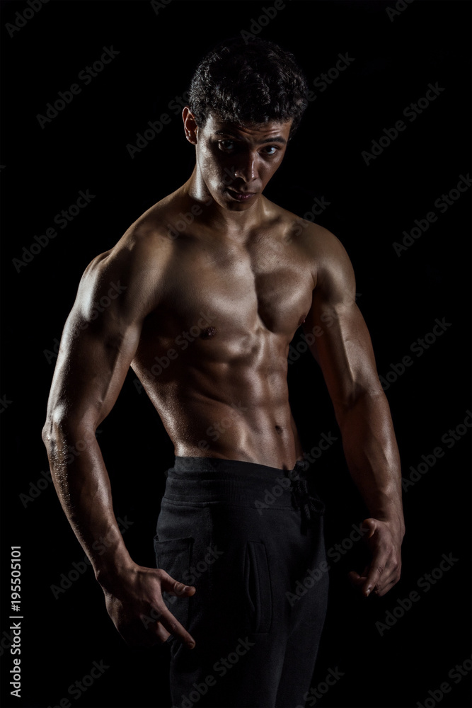 Highly retouched fitness model and bodybuilder, Looking and posing abs and chest. concept of power and strength. black background. Highly retouched fitness model and bodybuilder, Looking and posing abs and chest. concept of power and strength. black background.