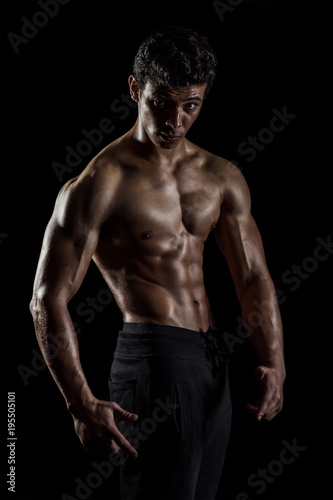 Highly retouched fitness model and bodybuilder, Looking and posing abs and chest. concept of power and strength. black background. © abdulrahman