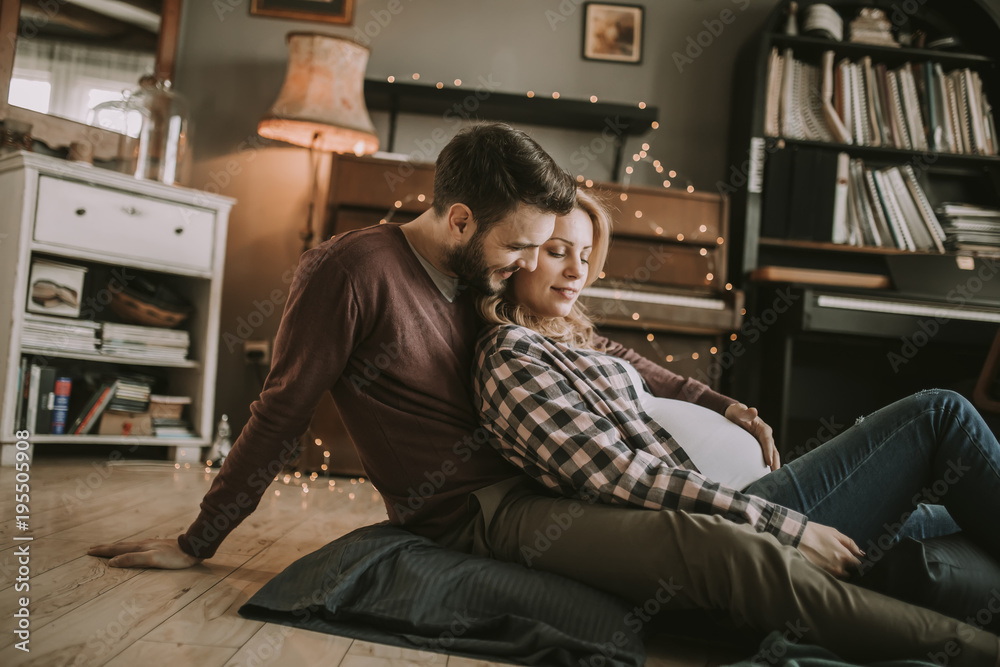 Pregnant woman with a husband sitting on the floor