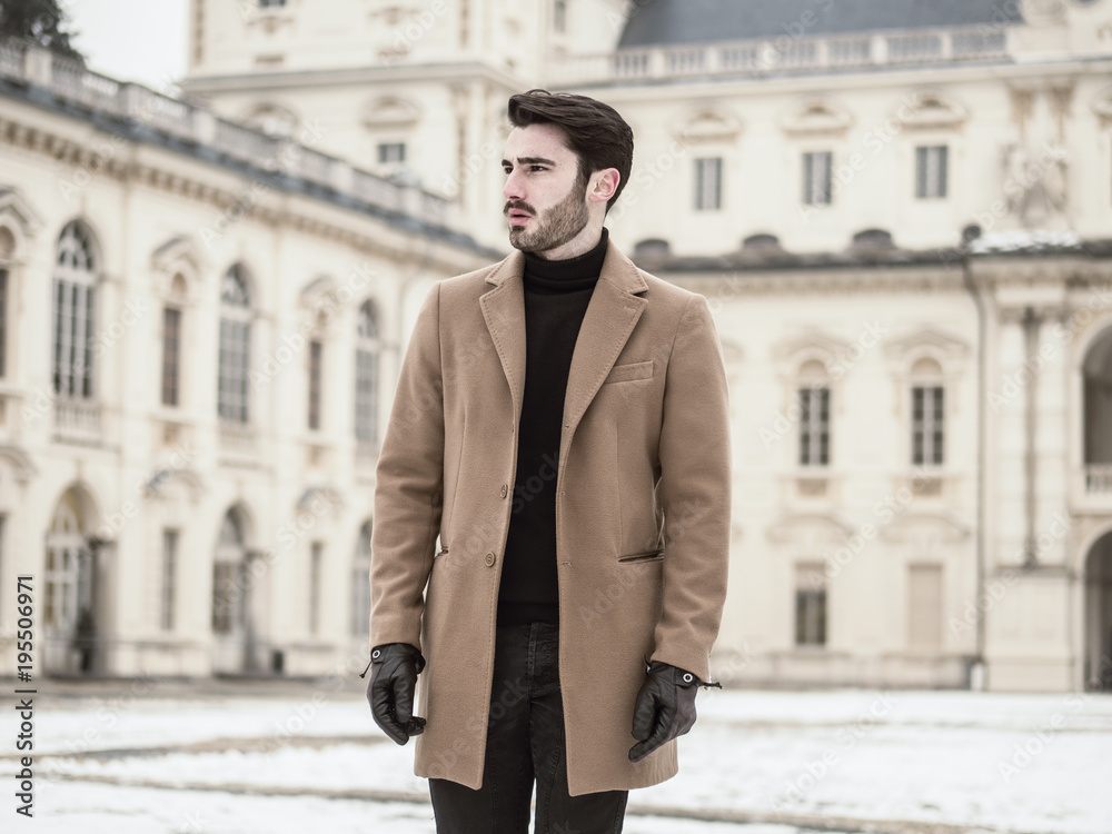 Handsome young man standing outside in winter, in snowy Turin, in Italy, in urban setting Handsome young man standing outside in winter, in snowy Turin, in Italy, in urban setting