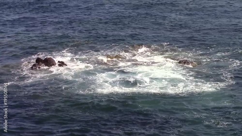 Sea waves  braking over exposed rocks during an incoming tide. 
