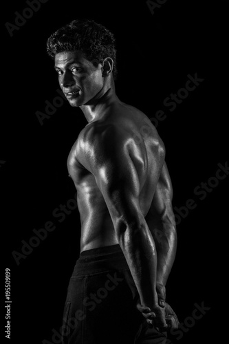 Highly retouched black and white fitness model and bodybuilder, Looking and posing triceps and back. Concept of power and strength. black background.