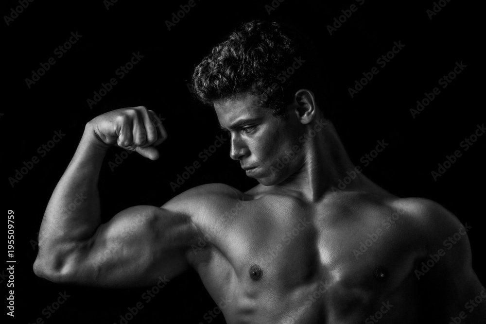 Highly retouched black and white fitness model and bodybuilder posing biceps. concept of strength. black background.