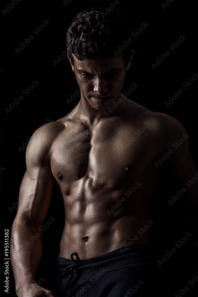 Highly retouched fitness model and bodybuilder, Looking and posing abs and chest. concept of power, strength and self-confidence. black background. Highly retouched fitness model and bodybuilder, Looking and posing abs and chest. concept of power, strength and self-confidence. black background.