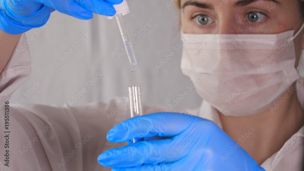 Laboratory work, a woman doctor holds a pipette, takes the test from a test tube, in a medical mask, in blue rubber gloves, analysis, dna.... Laboratory work, a woman doctor holds a pipette, takes the test from a test tube, in a medical mask, in blue rubber gloves, analysis, dna....