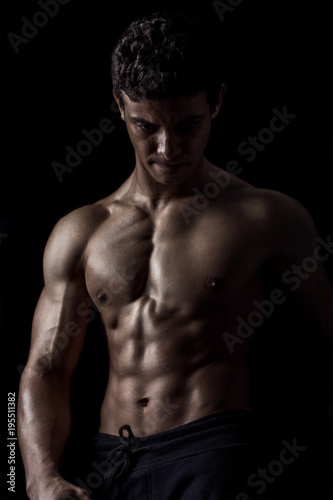 Highly retouched fitness model and bodybuilder, Looking and posing abs and chest. concept of power, strength and self-confidence. black background.