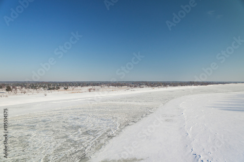 shot of snowy landscape with clear sky and frozen river