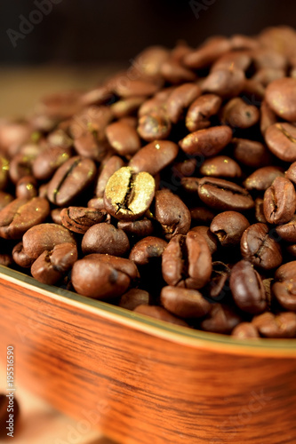 Golden roasted coffee bean among the others in a wooden bowl