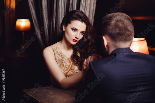 Young woman holds a man by the hand. Romance at night restaurant for Valentine Day.