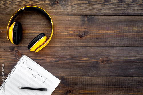 Work desk of modern composer. Music notes near headphones on dark wooden background top view copy space photo