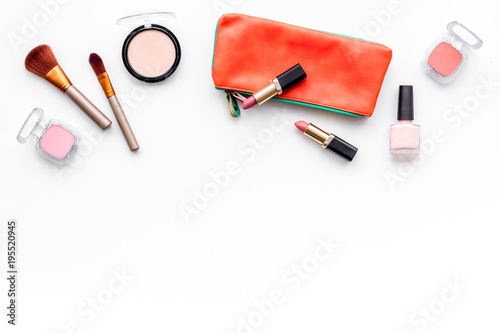 Decorative cosmetics background. Eyeshadow, rouge, brushes, lipstick in cosmetic bag on white top view copy space