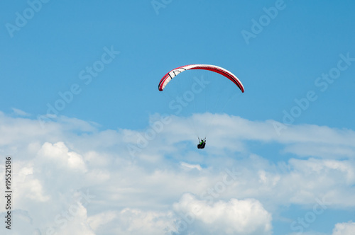 Paraglider flying in the blue sky against the background of clouds. Paragliding in the sky on a sunny day.