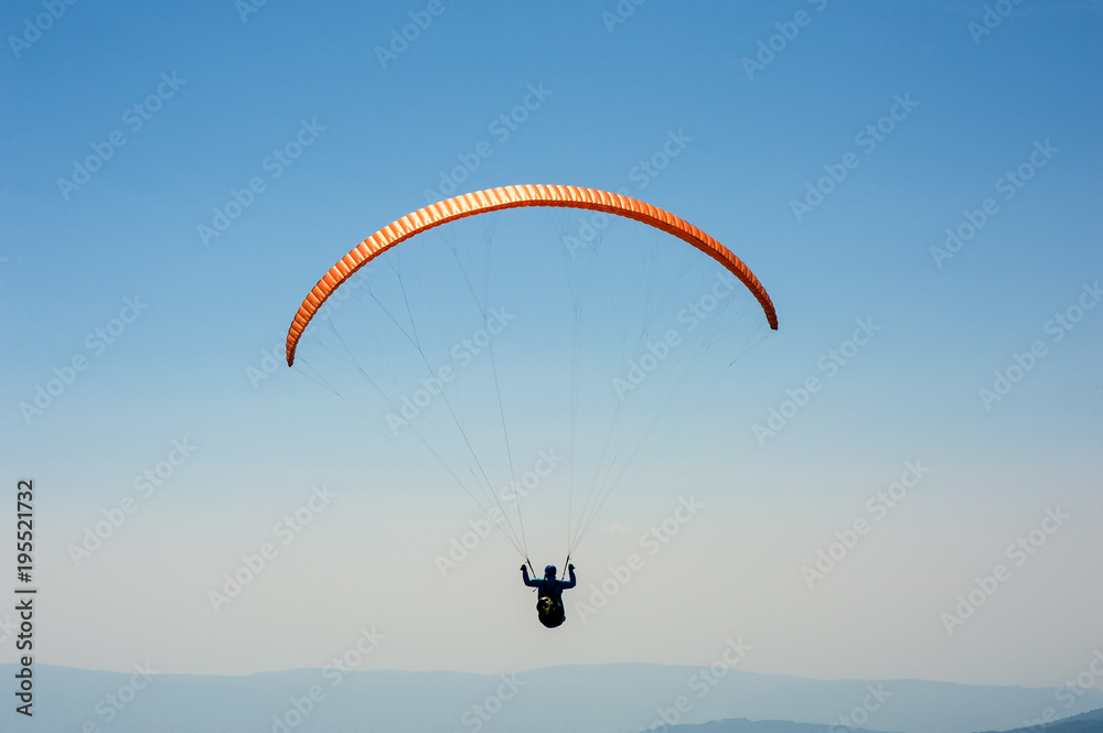 Paraglider flies over a mountain valley on a sunny summer day. Paragliding in the Carpathians in the summer. Paraglider flies over a mountain valley on a sunny summer day. Paragliding in the Carpathians in the summer.