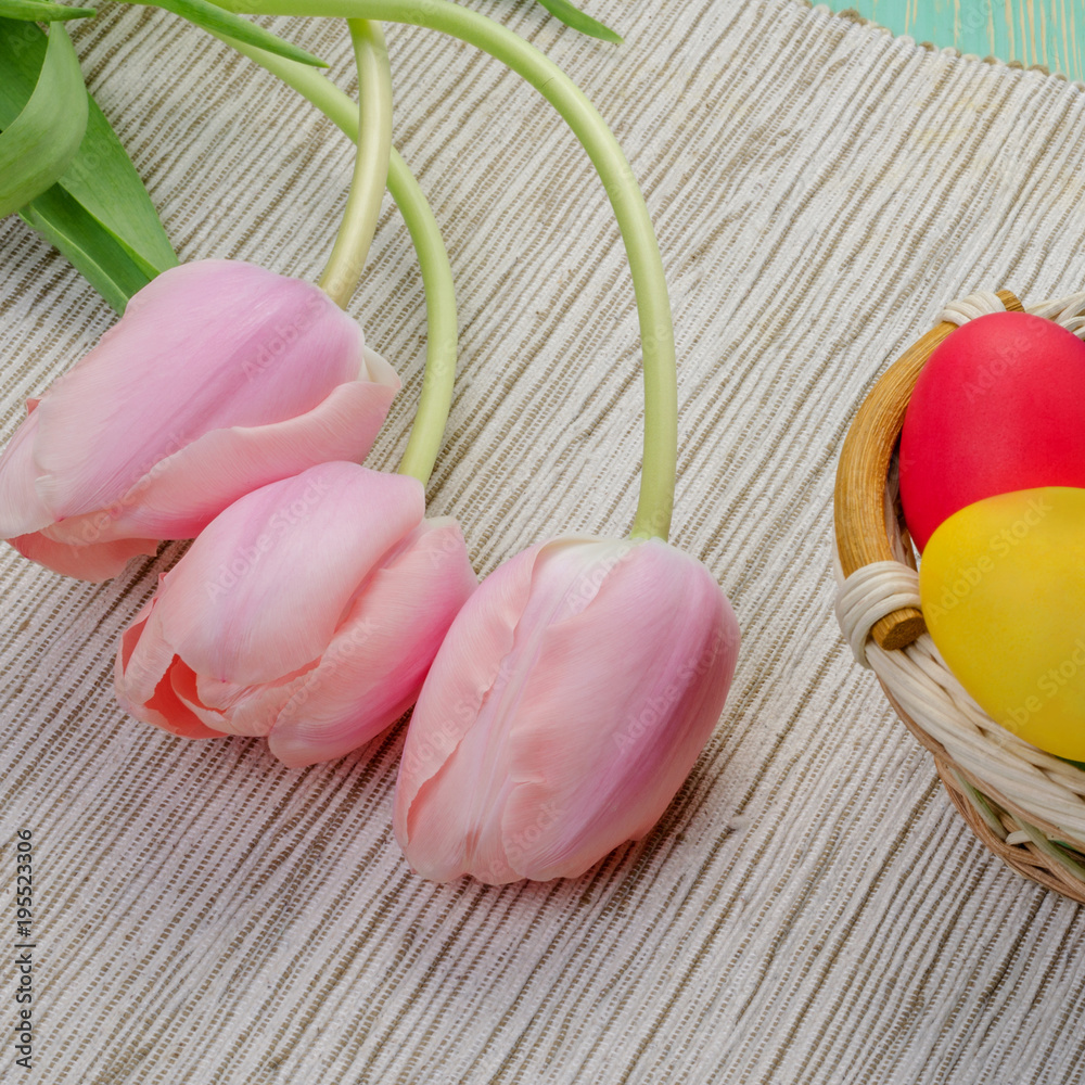 Basket of colorful easter eggs with pink tulips. Concept of the religious holiday Easter. Square. Basket of colorful easter eggs with pink tulips. Concept of the religious holiday Easter. Square.