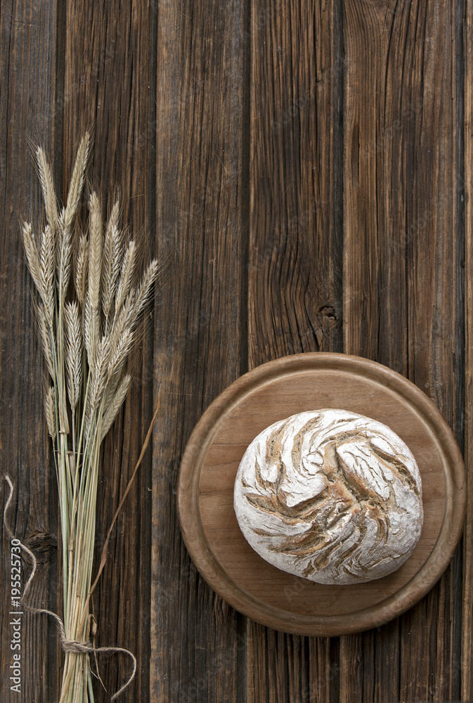 Freshly baked traditional bread andand Wheat Ears on the Wooden Table. Harvest and Bakery concept. Top view, close-up on a vintage wooden background Freshly baked traditional bread andand Wheat Ears on the Wooden Table. Harvest and Bakery concept. Top view, close-up on a vintage wooden background
