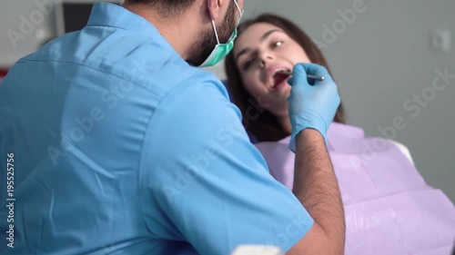 Dentist using periodontal probe, smiling patient opening the mouth, doctor explaining the case afterwards, indoor shot in clean modern dental office