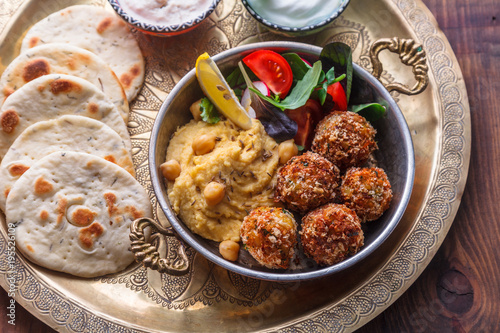 Photos Hummus, falafel, salad and pita in a copper pan