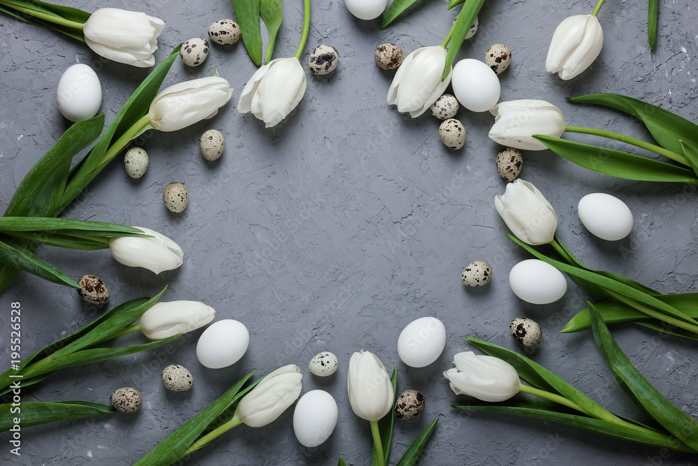 A circle of white tulips and chicken and quail eggs on a gray concrete background. Top view. Flat lay. Postcard for Easter and Spring Holidays. A circle of white tulips and chicken and quail eggs on a gray concrete background. Top view. Flat lay. Postcard for Easter and Spring Holidays.
