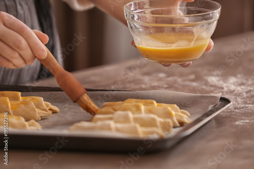 Foto Woman spreading egg yolk onto croissants at table