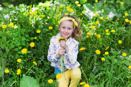 Portrait of cute little happy child girl or kid with dandelion flowers bouquet standing on a green meadow, mother day concept © viclin