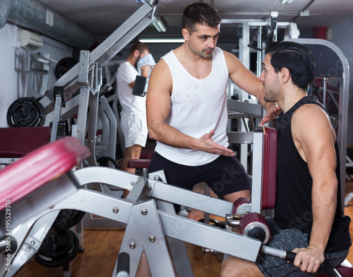 Man during training with  instructor in gym photo