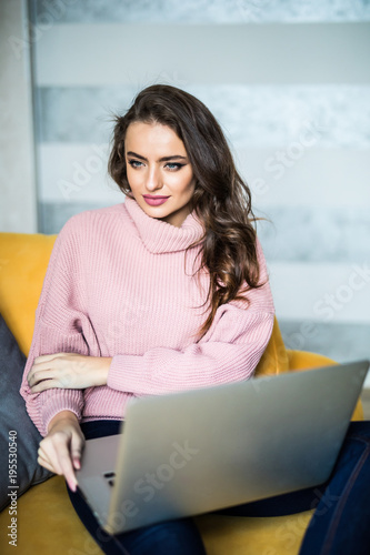 Casual young woman using laptop in living room at home photo