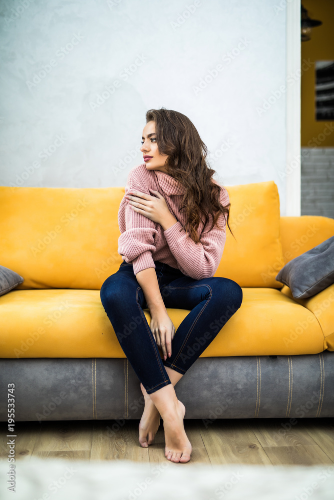 Obraz premium Young woman sitting on her white sofa at home