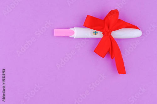 Photo of ultrasound and positive results pregnancy test with red bow on pink background..