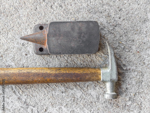 Old small hammer and miniature anvil with concrete background